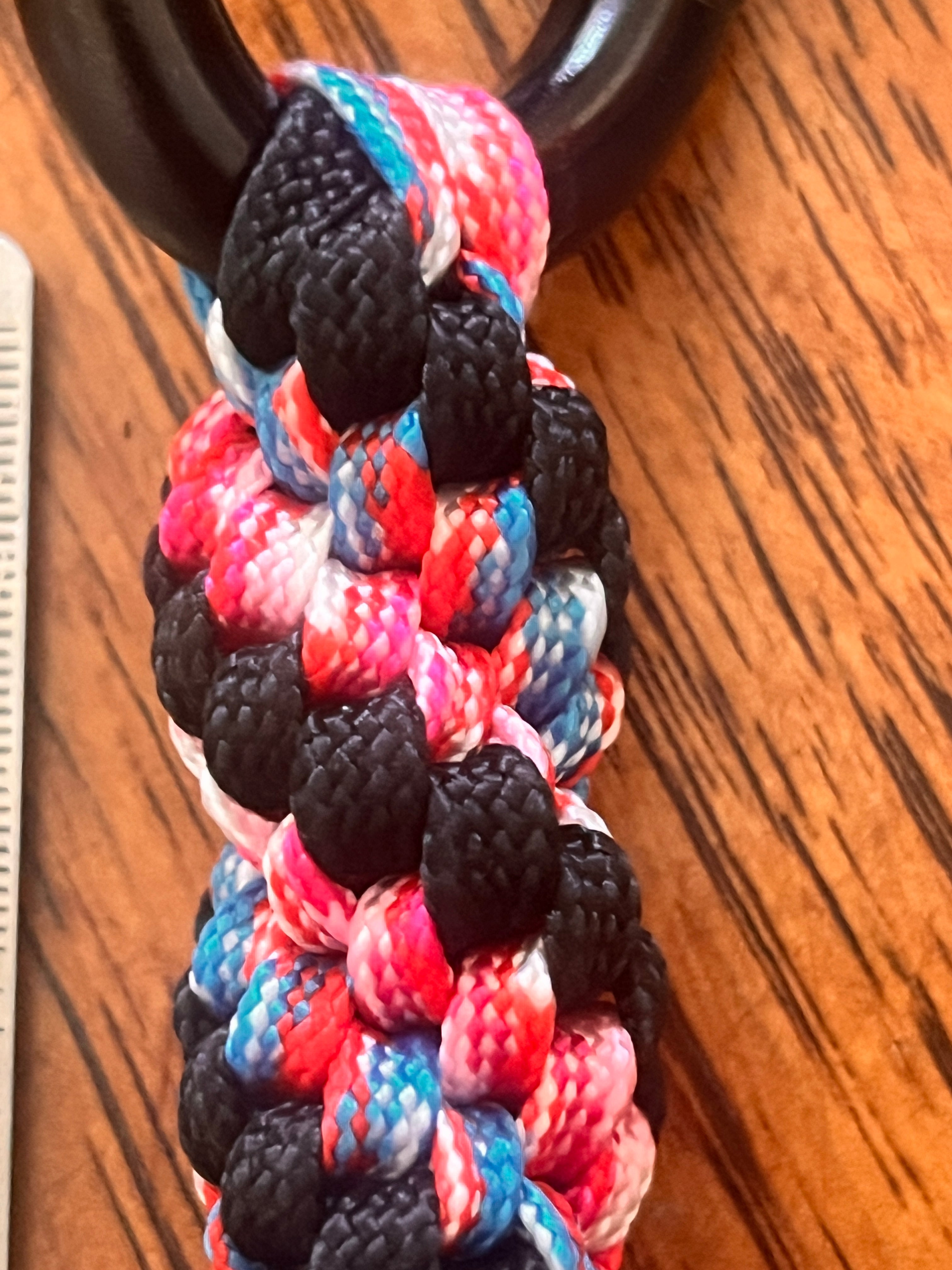 Colorful braided cord with black, red, and blue pattern on a wooden surface